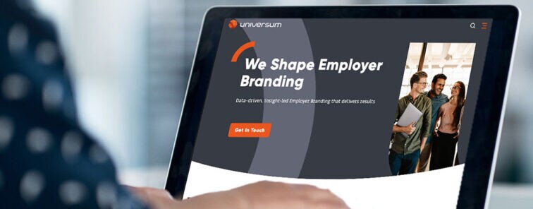 Auf dem Laptop ist die Webseite von Universum aufgerufen, worauf groß der Titel steht: We Shape Employer Branding