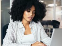 Frau mit Afro sitzt vor ihrem Laptop