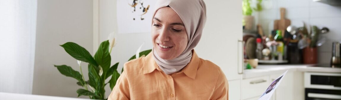Lächelnde Frau mit Hijab, die zu Hause Rechnungen prüft