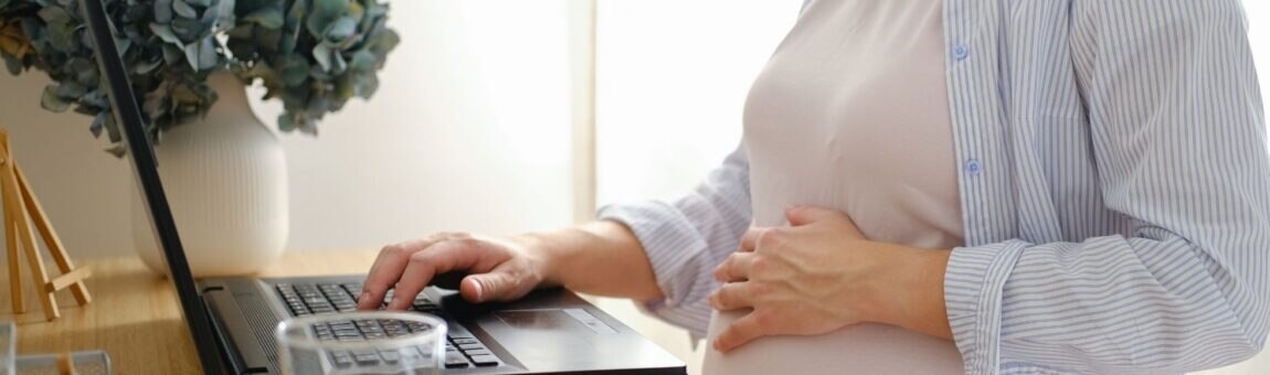 Eine schwangere Frau arbeitet am Laptop