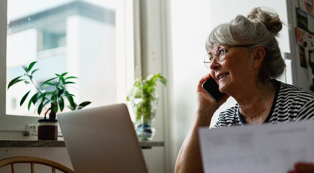 Ältere Frau am Laptop beim Telefonieren