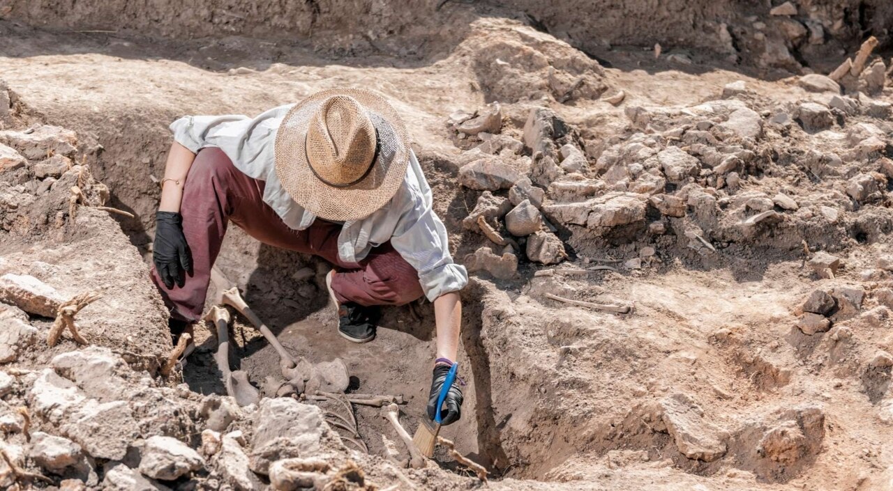 Archäologe in archäologischer Ausgrabungsstätte gräbt ein Skelett aus