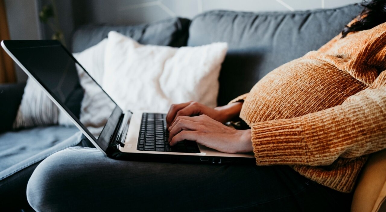 Eine schwangere Frau sitzt vor ihrem Laptop