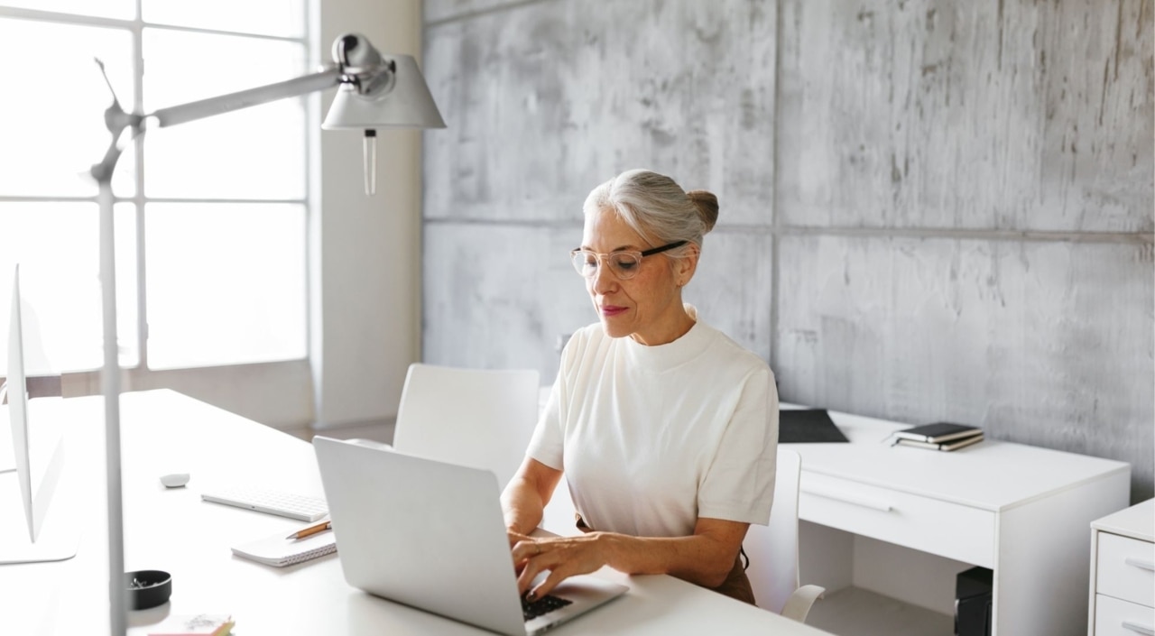 Eine Frau mit grauen Haaren sitzt am Laptop