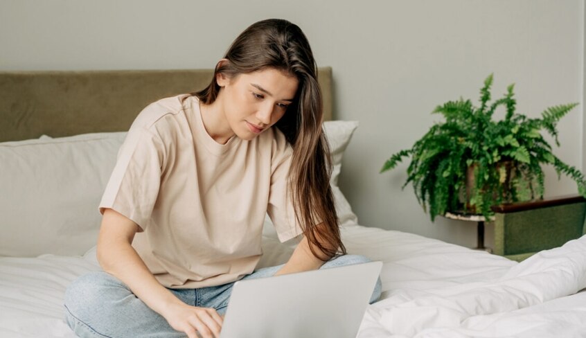 Eine junge Frau sitzt vor einem Laptop und recherchiert im Internet.