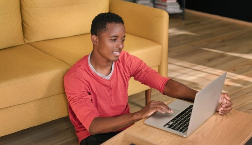 Ein junger Mann sitzt vor seinem Laptop