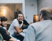 Mehrere Personen im Teammeeting beim aktiven Zuhören, während eine Person im Vordergrund spricht