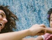 Blick von oben auf eine glückliche Mutter mit ihrem Baby auf dem Wohnzimmerteppich.