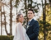 Ehepaar steht am Hochzeitstag lachend im Wald