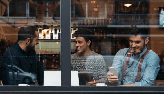 3 Männer sitzen in einem Cafe mit Laptop