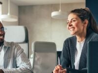 Eine junge Frau und ein junger Mann sitzen lächelnd zusammen.