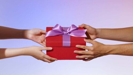 Vier Hände halten ein Geschenk