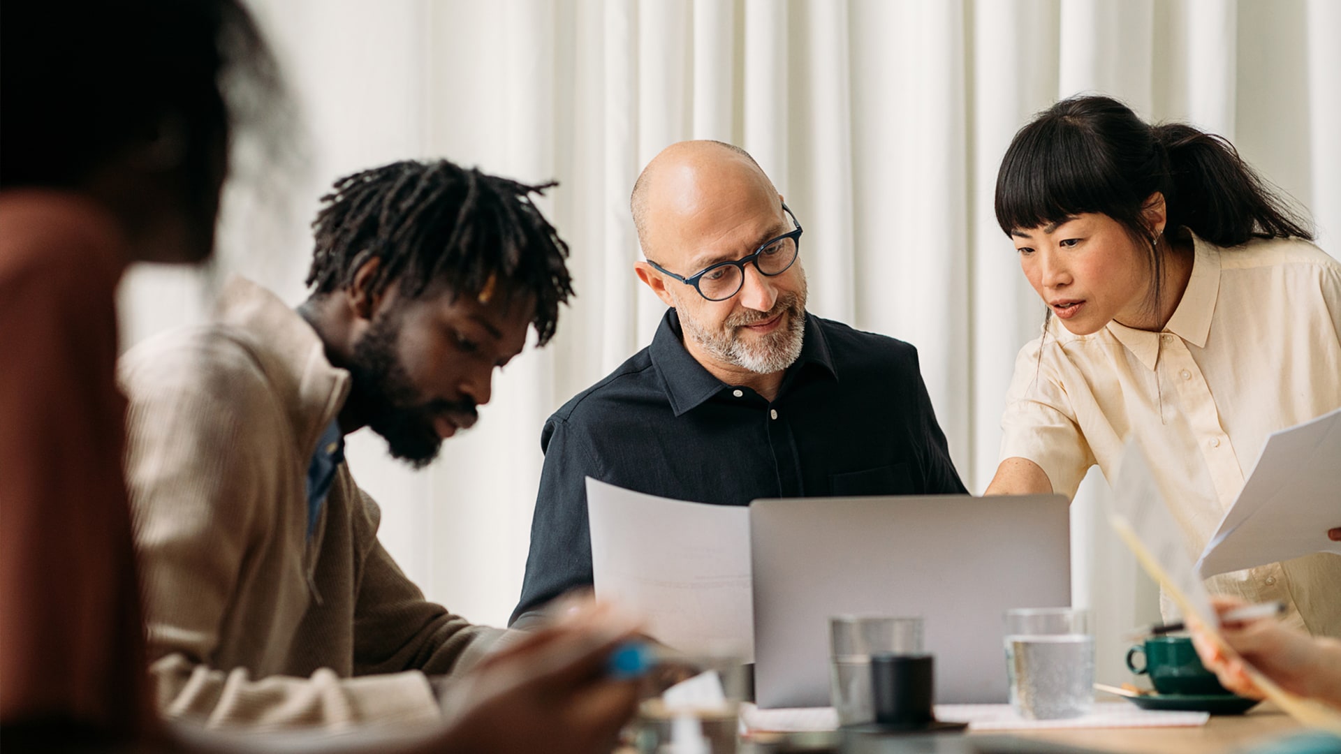 Mehrere Personen sitzen im Büro an einem Konferenztisch und haben eine Besprechung.