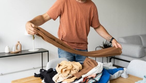 Ein Mann steht im Wohnzimmer und macht Wäsche.