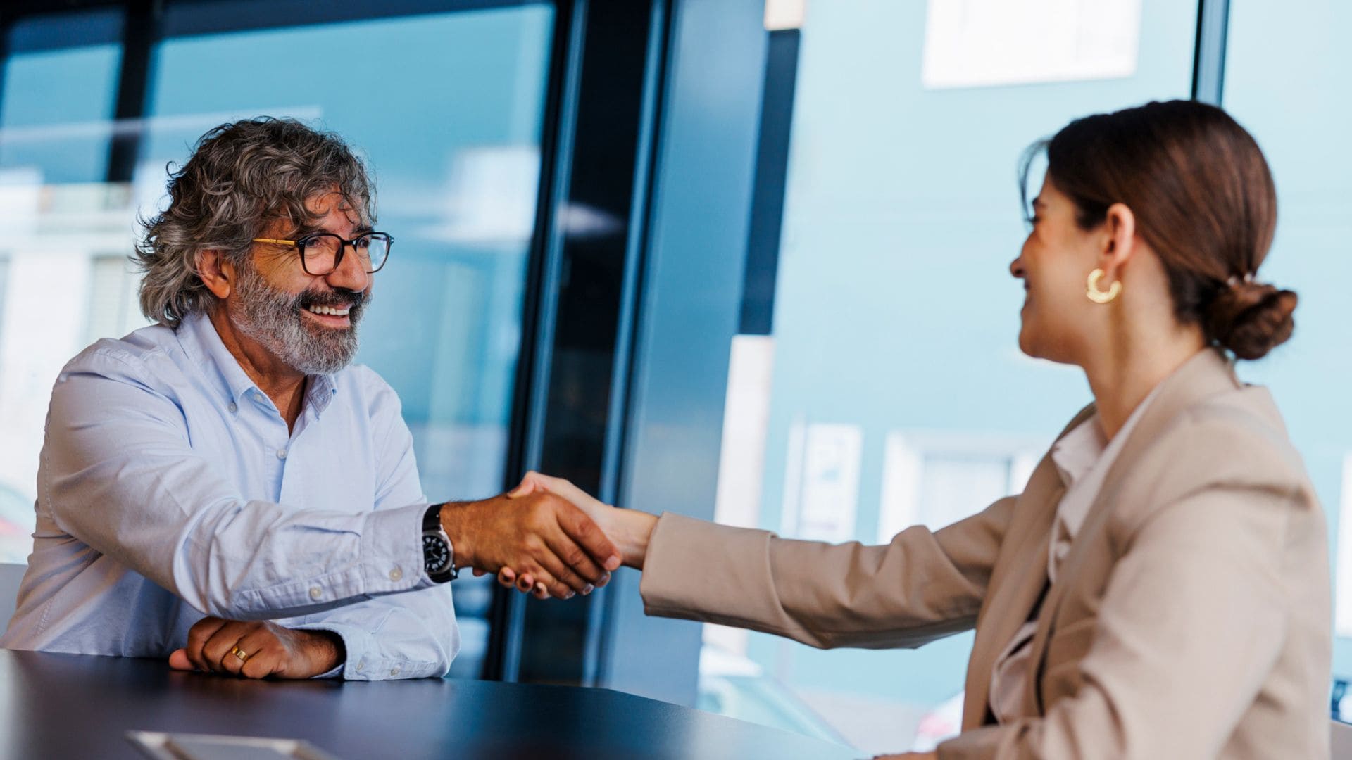 Ein Mann und eine Frau im Büro geben sich die Hand