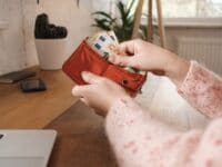 Eine Frau hält ein Portemonnaie in der Hand, aus dem sie Geldscheine herausholt.