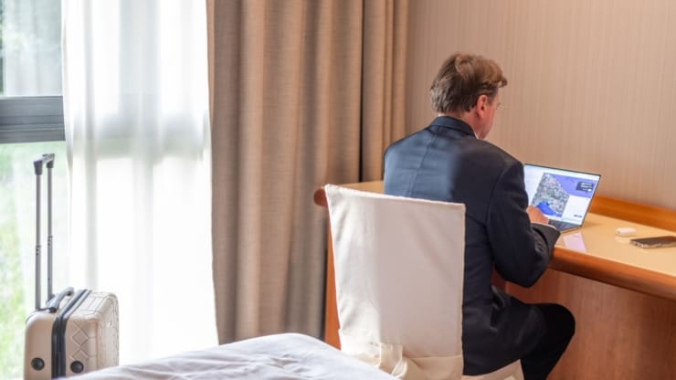 Mann arbeitet in Hotelzimmer an Laptop