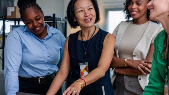 Eine vielfältige Gruppe von Frauen arbeitet gemeinsam an einem Projekt zum Entgelttransparenzgesetz in einer modernen Büroumgebung.