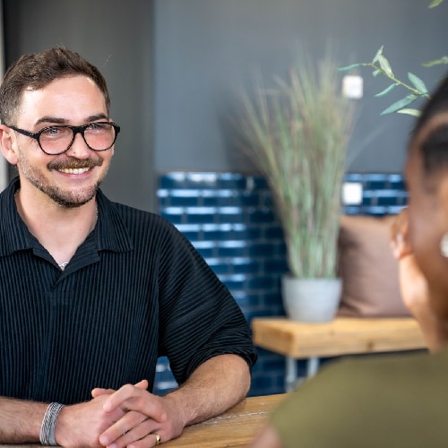 Stepstones Senior Talent Acquisition Manager Christopher Lennartz sitzt einer Frau mit Zöpfen gegenüber und lächelt sie an.